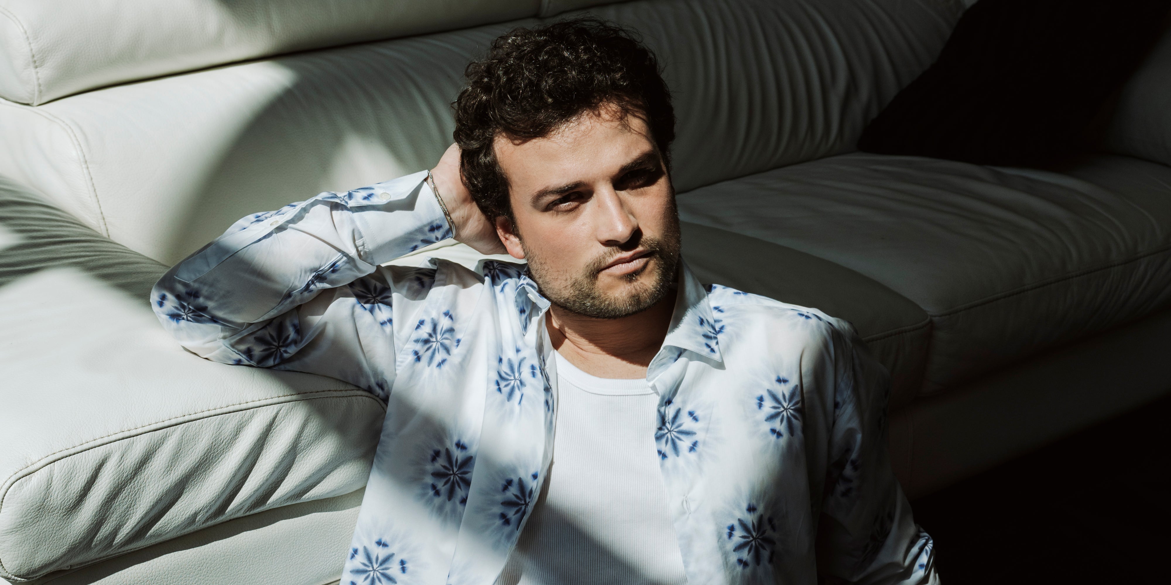 Camicia tie dye indossata da modello in posa sul divano