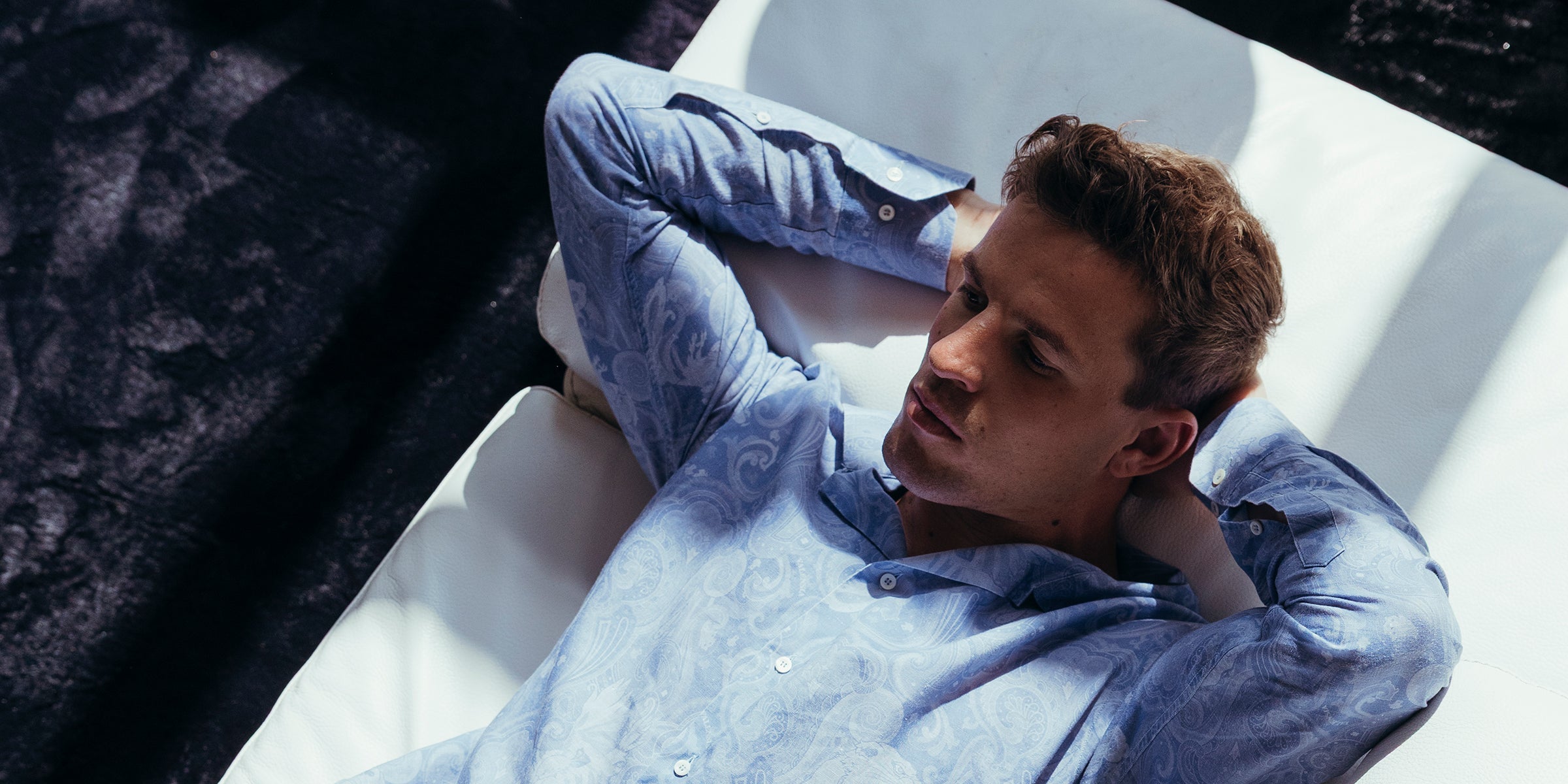 Camicia fantasia azzurra misto lino indossata da modello in posa sul divano